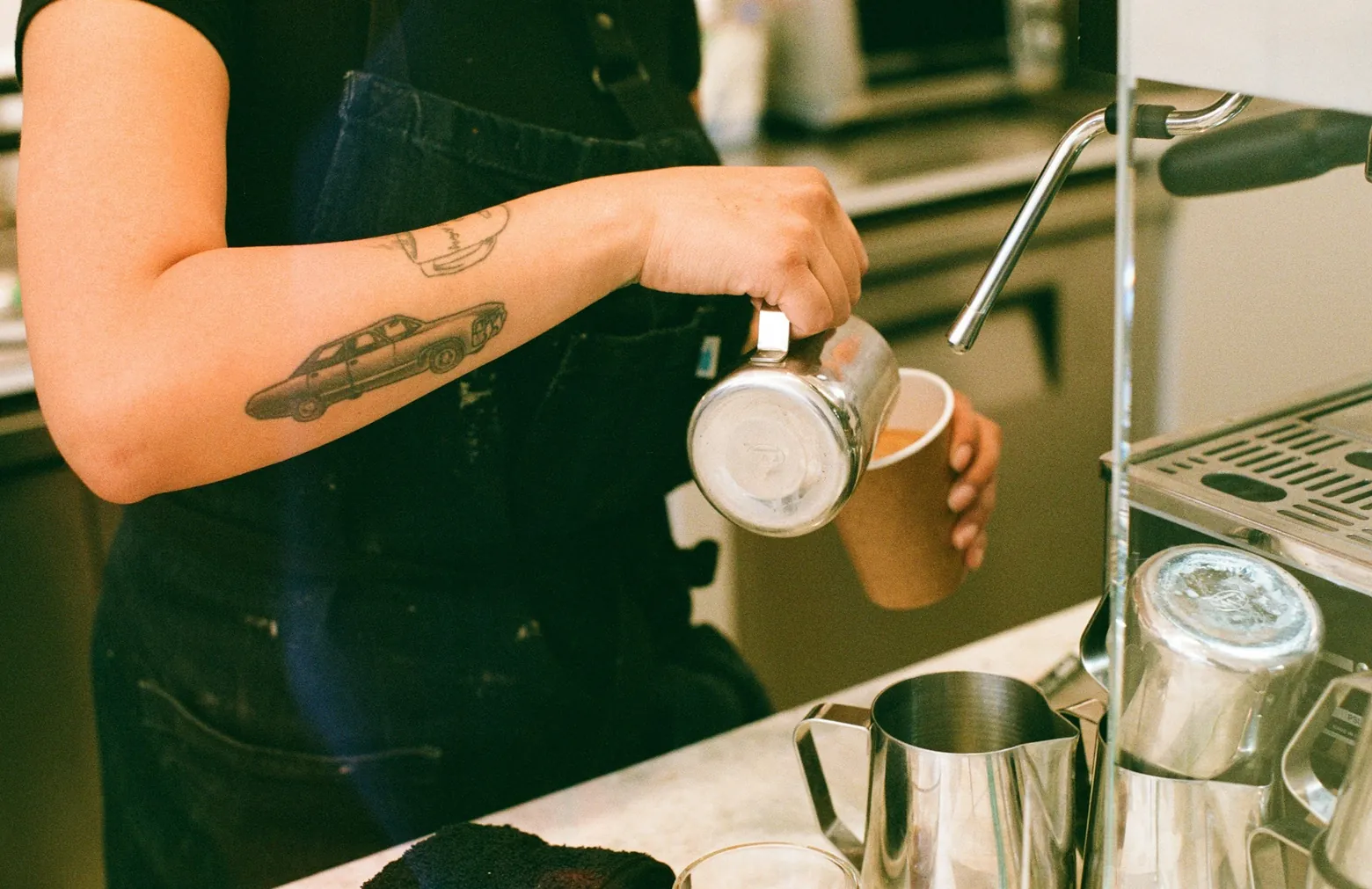 Barista pouring steamed milk into a takeaway coffee