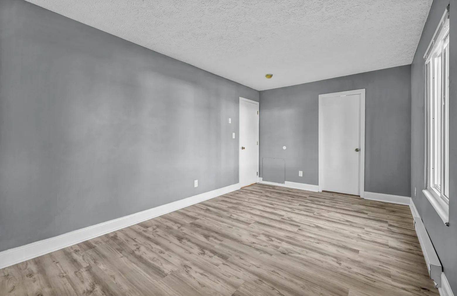 Newly finished empty room with grey walls and wood flooring