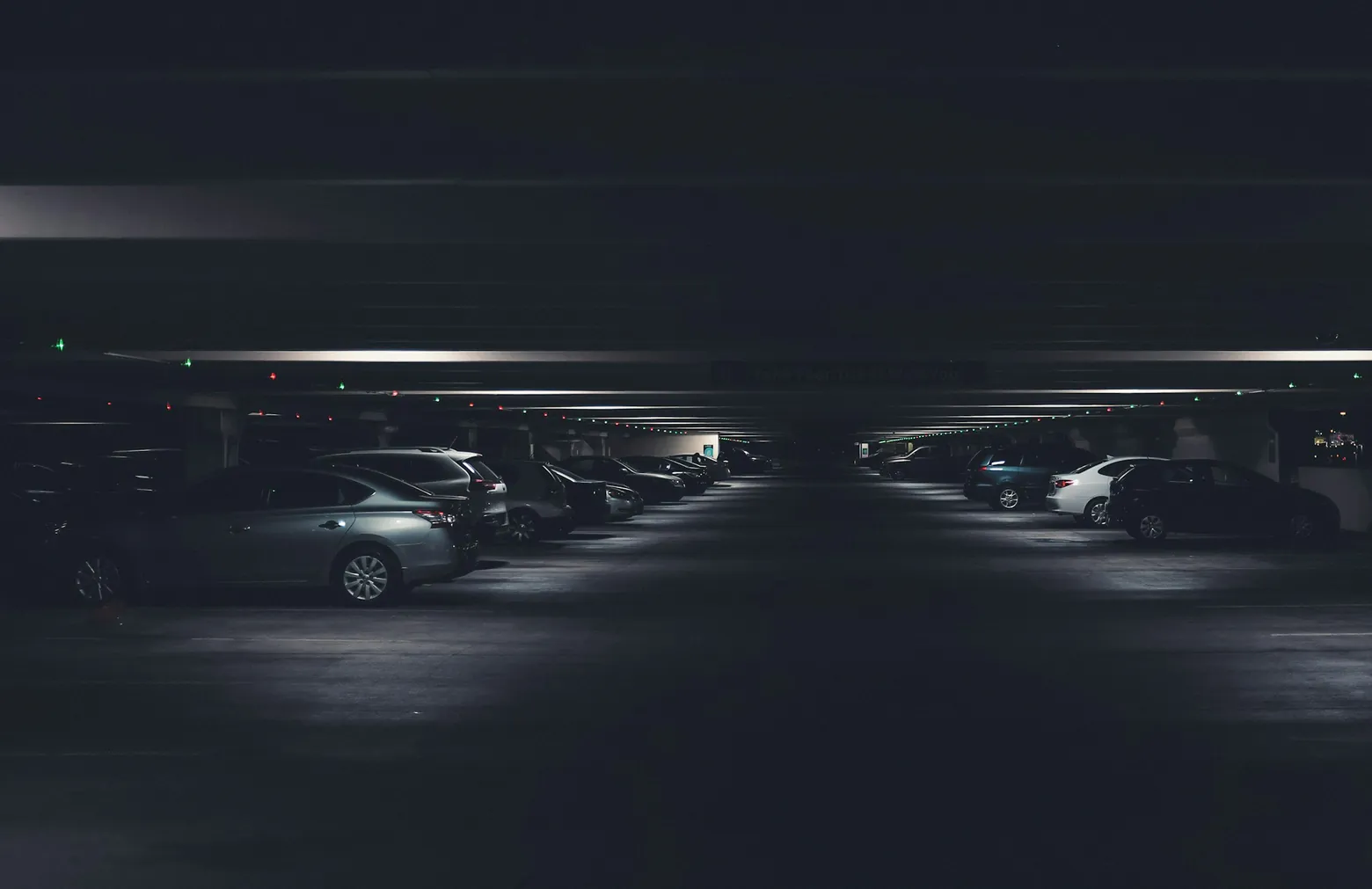 Rows of parked cars in a dimly lit underground parking garage